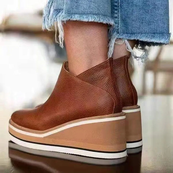 A woman wearing sleek minimalist ankle boots with jeans on a city break.
