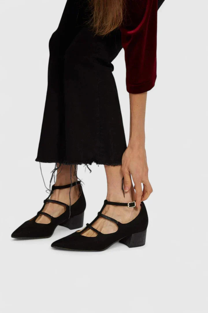A woman standing gracefully in low wide-fit comfort heels with a cushioned footbed.