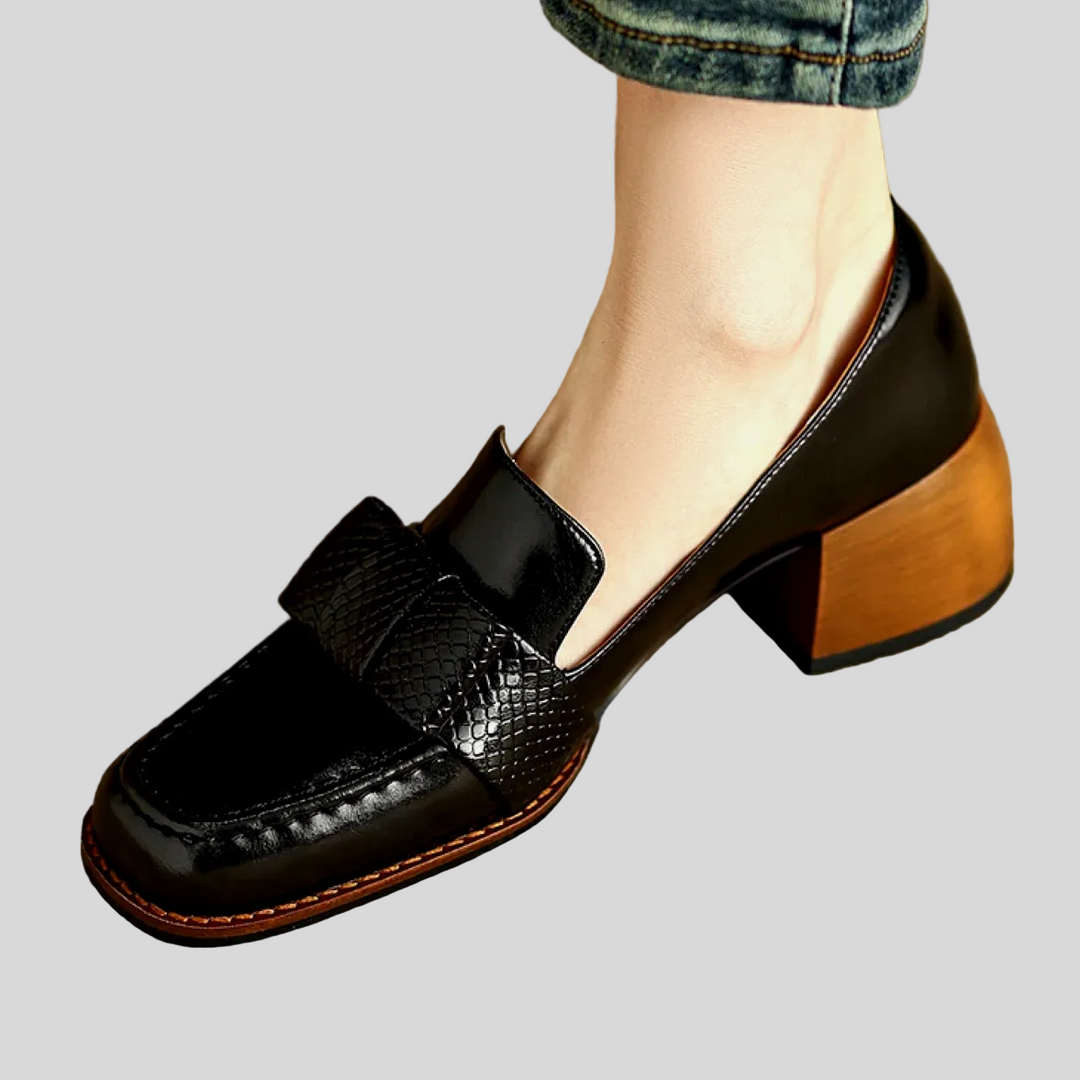 A woman wearing classic loafers with a subtle knot detail and tailored pants