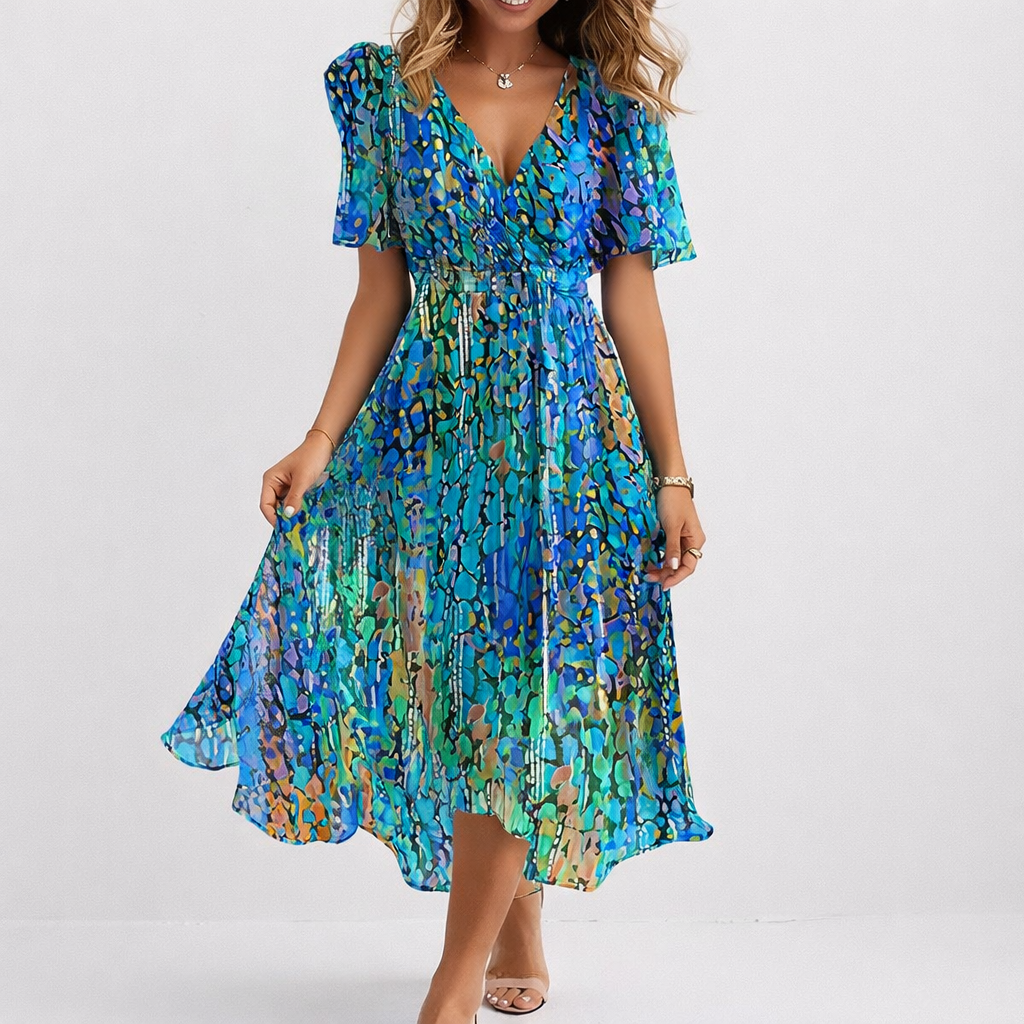 Woman wearing the Sharon airy blue midi dress, the asymmetric hem catching the breeze by the sea.