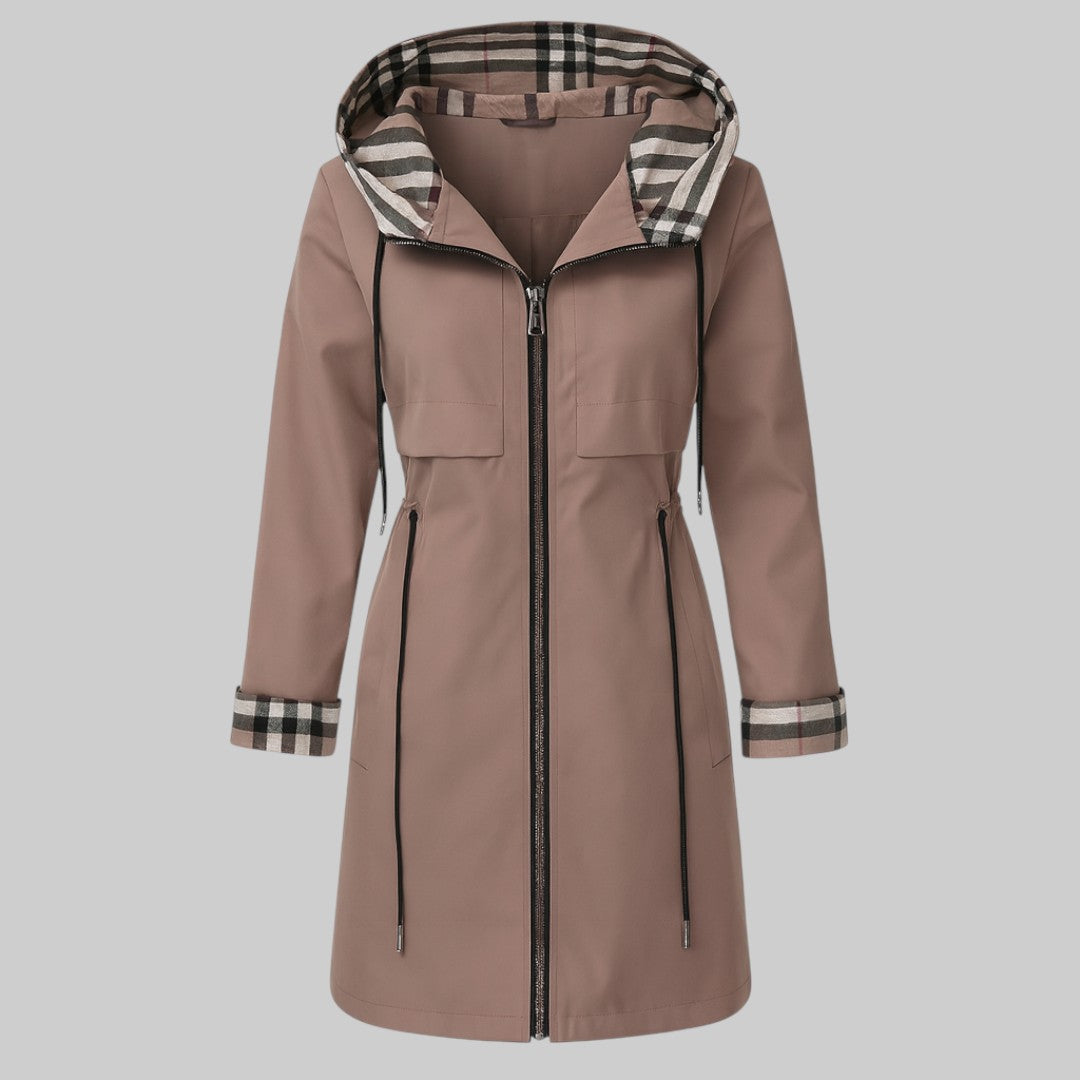 A woman wearing a waisted zip-up coat, standing outdoors on a cold day