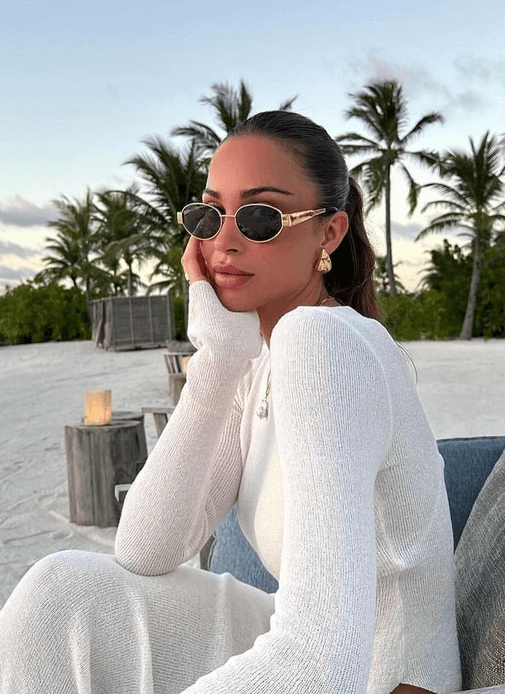 A woman wearing elegant vintage-style gold sunglasses on a sunny day out.
