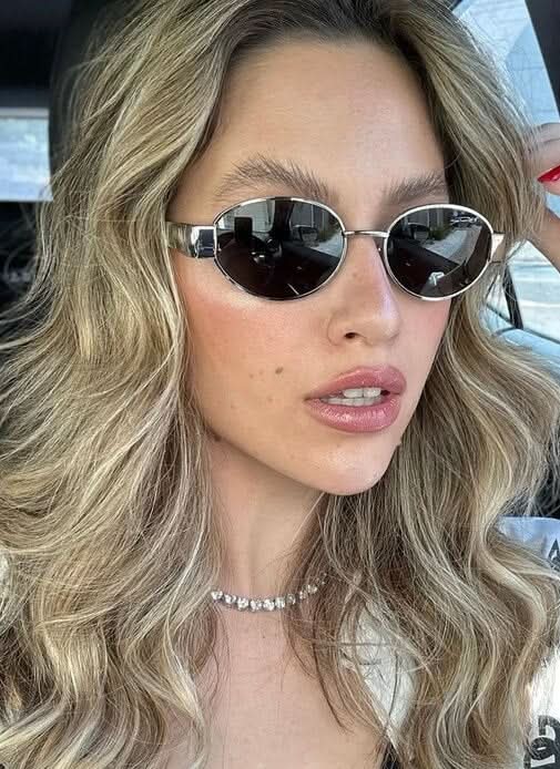 A woman wearing elegant vintage-style gold sunglasses on a sunny day out.