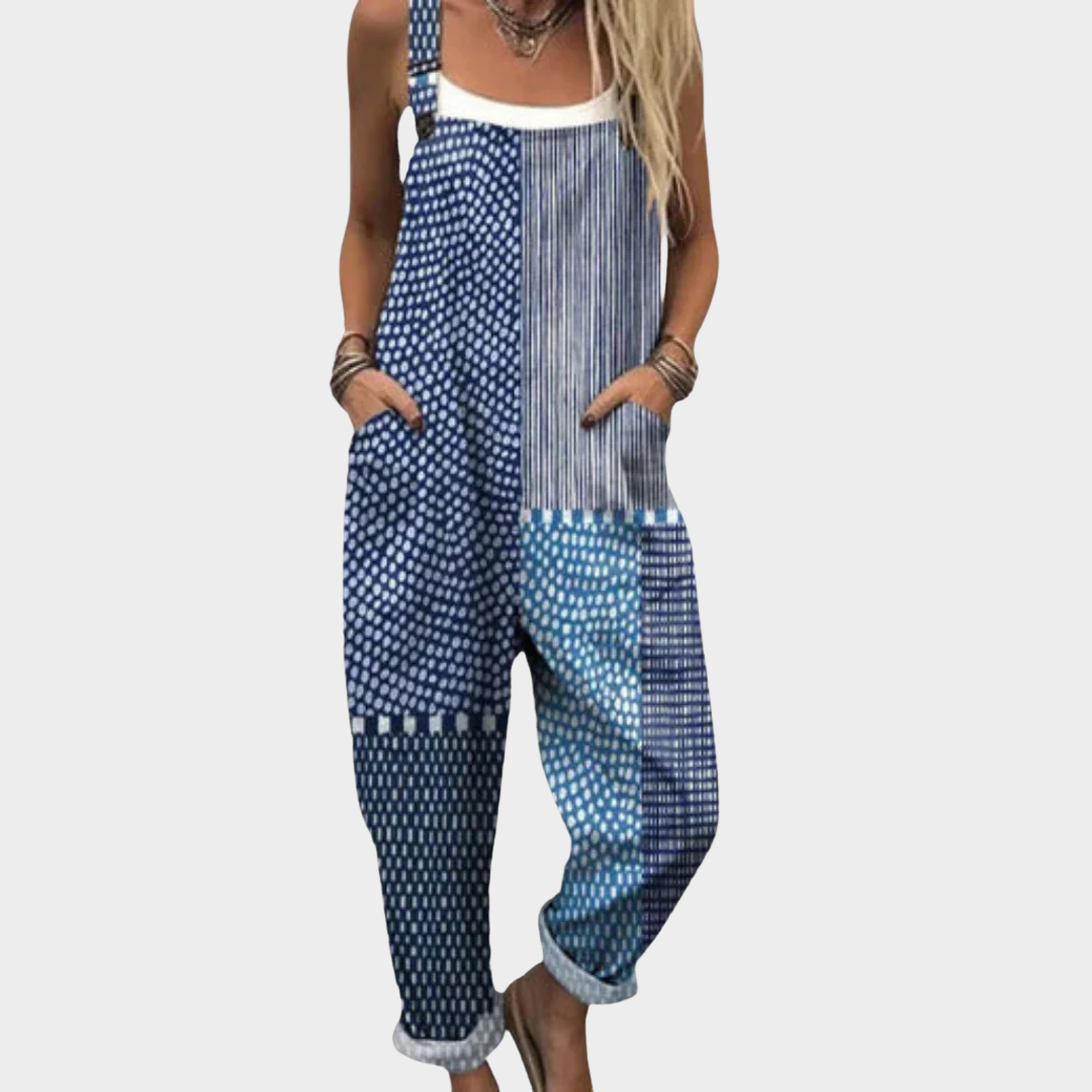 Woman wearing blue and white boho patchwork overalls with dots and stripes, adjustable straps, relaxed and free-spirited.