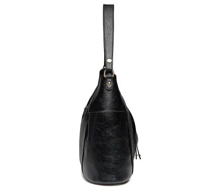 A woman wearing a fringed shoulder bag that sways gently as she walks through town.
