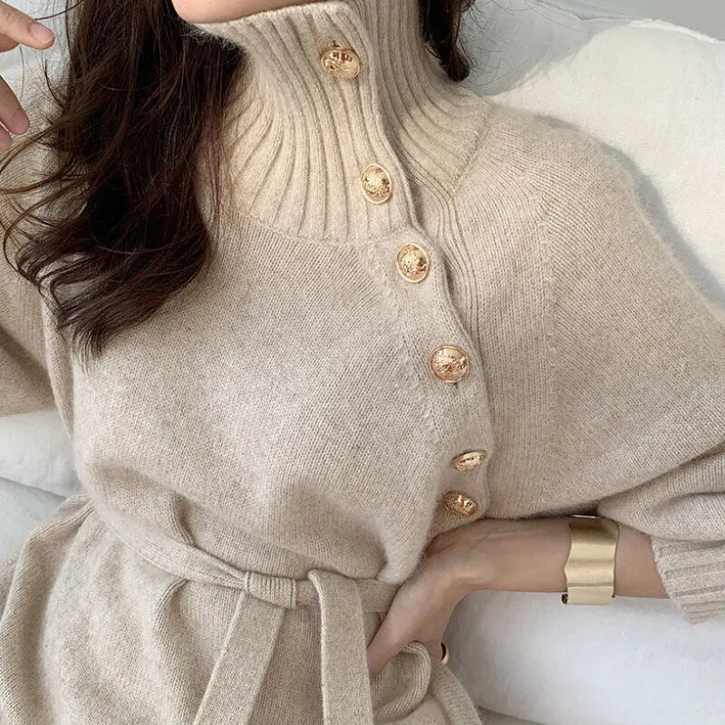 Woman in the Diana cosy wrap dress with gold-tone buttons and a waist tie, holding a warm drink at home.