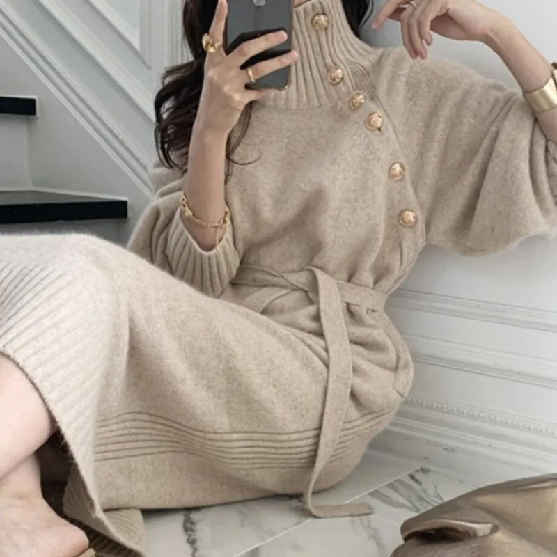 Woman in the Diana cosy wrap dress with gold-tone buttons and a waist tie, holding a warm drink at home.