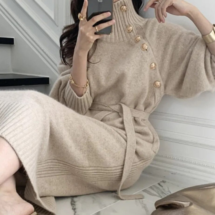 Woman in the Diana cosy wrap dress with gold-tone buttons and a waist tie, holding a warm drink at home.