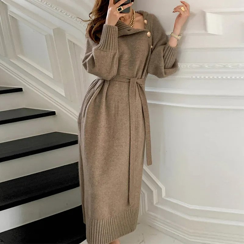 Woman in the Diana cosy wrap dress with gold-tone buttons and a waist tie, holding a warm drink at home.