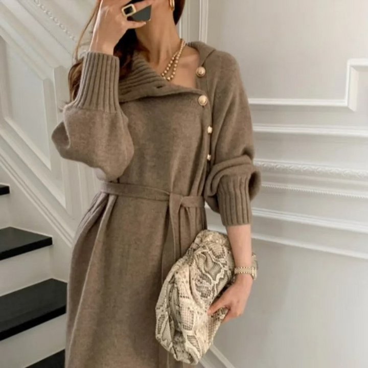 Woman in the Diana cosy wrap dress with gold-tone buttons and a waist tie, holding a warm drink at home.