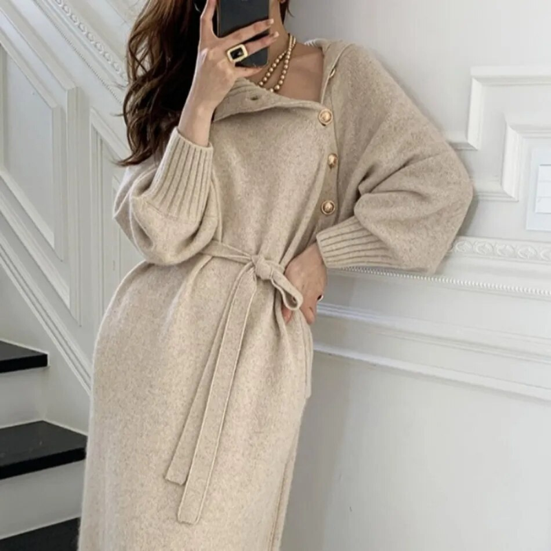 Woman in the Diana cosy wrap dress with gold-tone buttons and a waist tie, holding a warm drink at home.