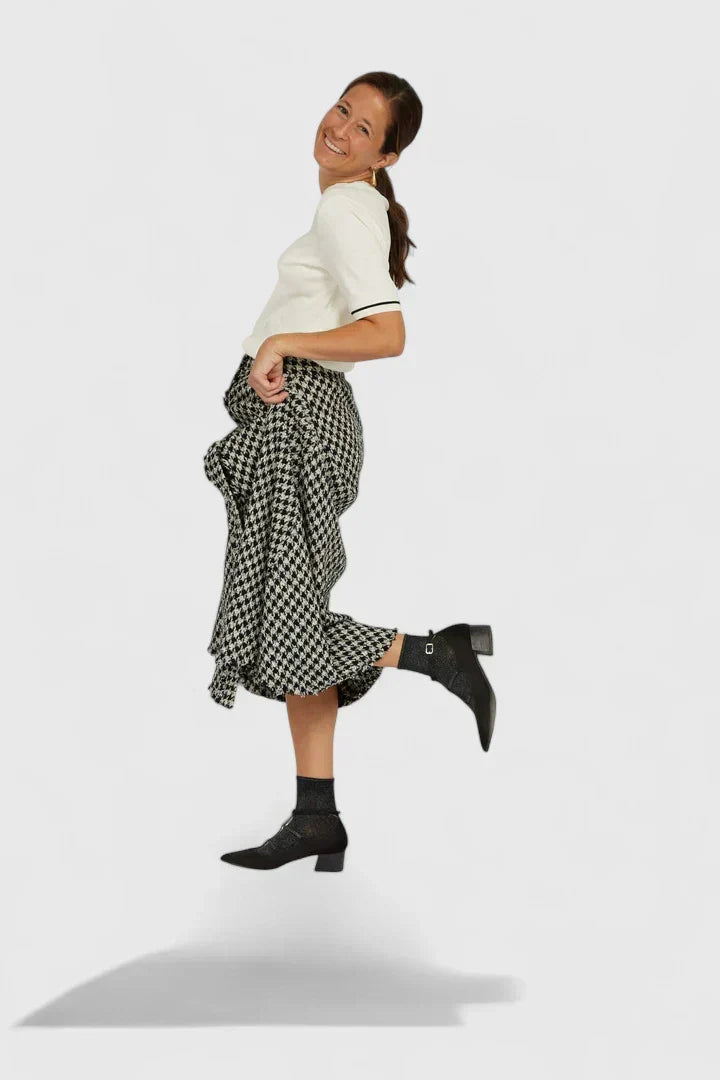 A woman walking through the city in black pointed-toe block heels with slim ankle straps, relaxed and confident.