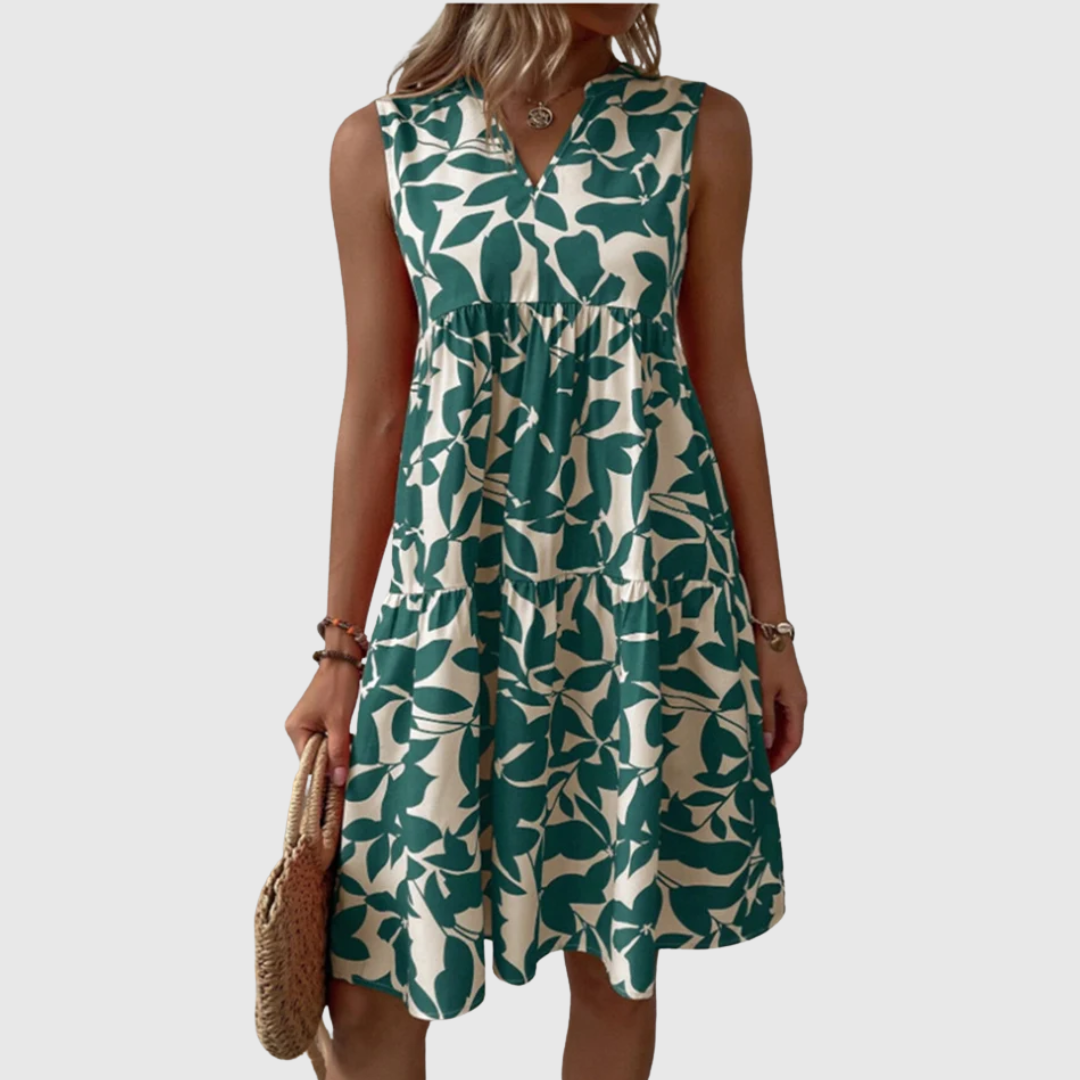 Woman wearing the Deborah sleeveless leaf-print midi dress in green, relaxing outdoors on a warm afternoon.