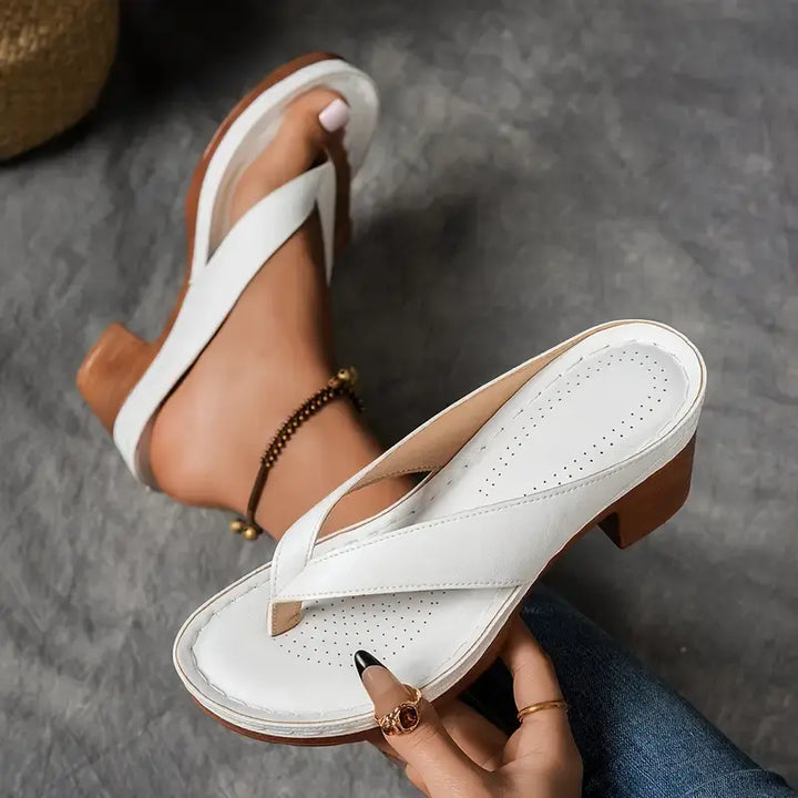 A woman wearing gold block heel sandals with a toe-post strap at an evening event.