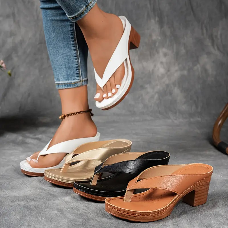 A woman wearing gold block heel sandals with a toe-post strap at an evening event.