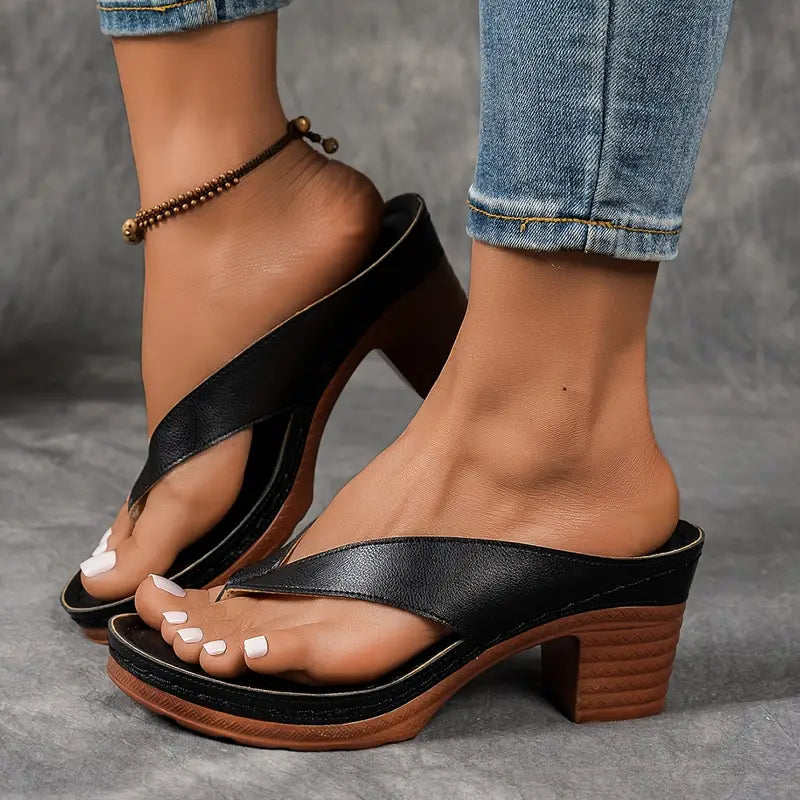 A woman wearing gold block heel sandals with a toe-post strap at an evening event.