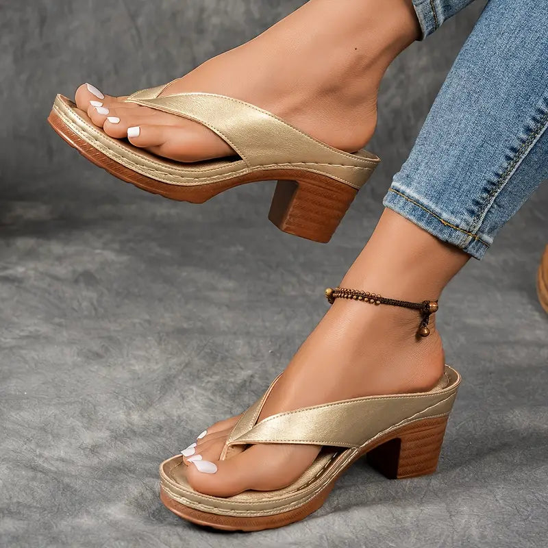 A woman wearing gold block heel sandals with a toe-post strap at an evening event.