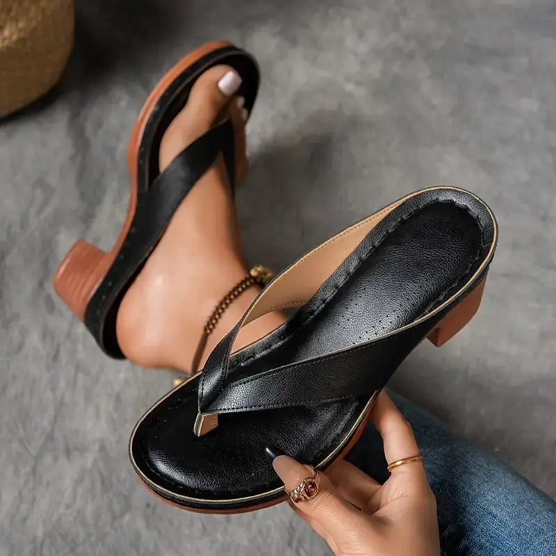 A woman wearing gold block heel sandals with a toe-post strap at an evening event.