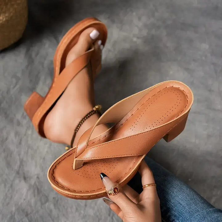 A woman wearing gold block heel sandals with a toe-post strap at an evening event.