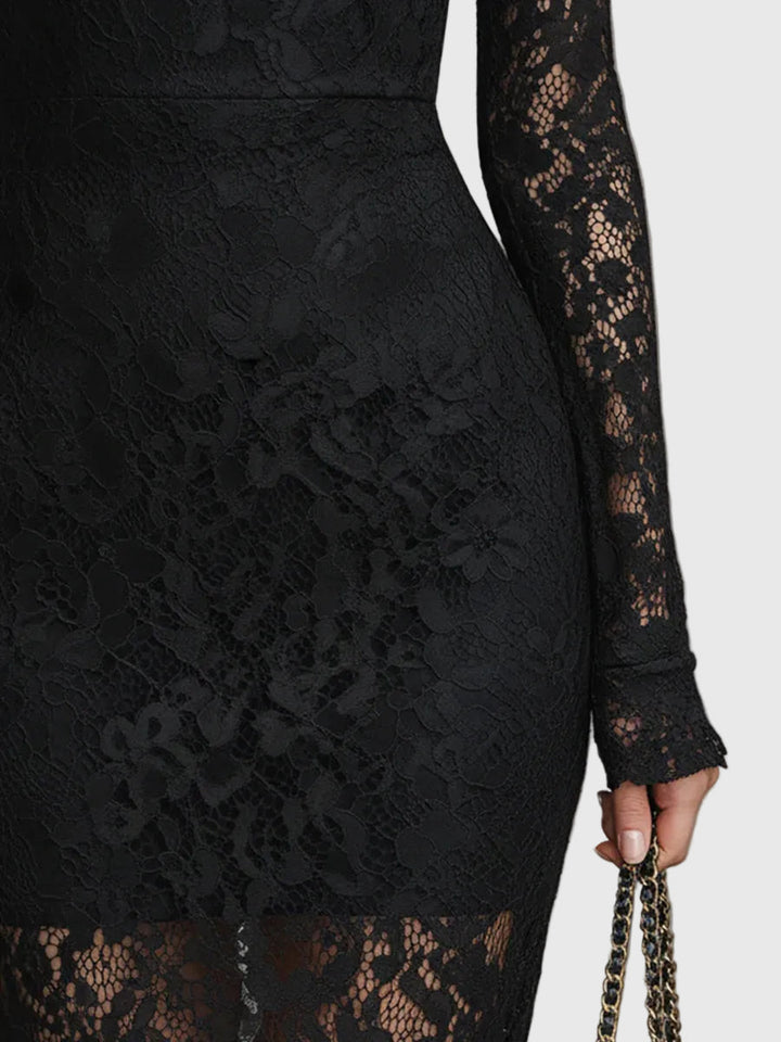 Woman wearing a fitted black maxi dress with a delicately textured skirt that flares out towards the hem.