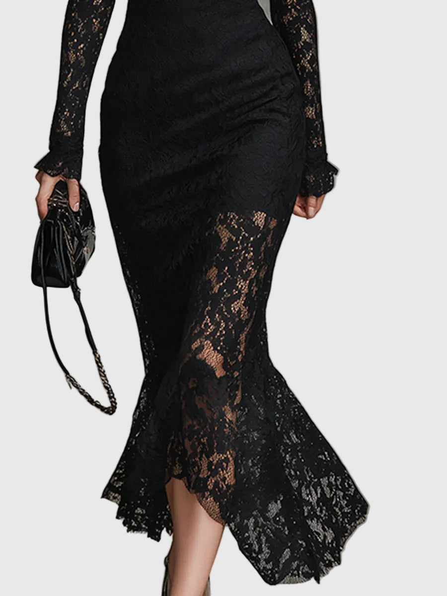 Woman wearing a fitted black maxi dress with a delicately textured skirt that flares out towards the hem.