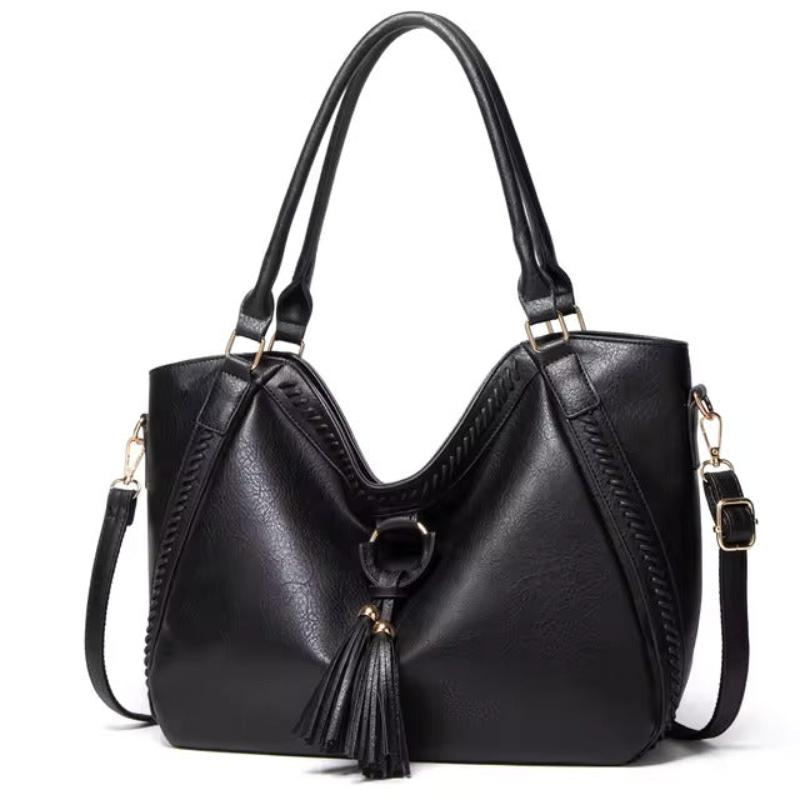 A woman carrying a soft tasselled shoulder bag while out for a walk in town.