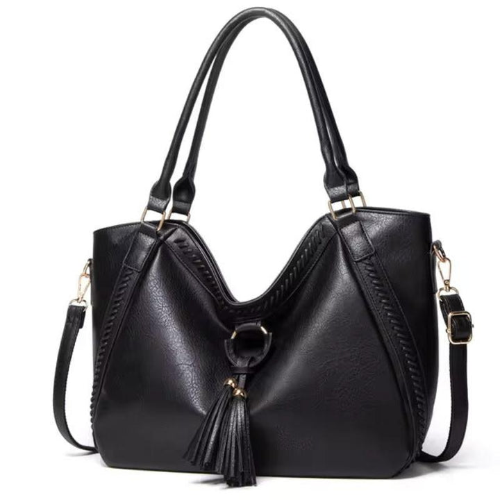 A woman carrying a soft tasselled shoulder bag while out for a walk in town.