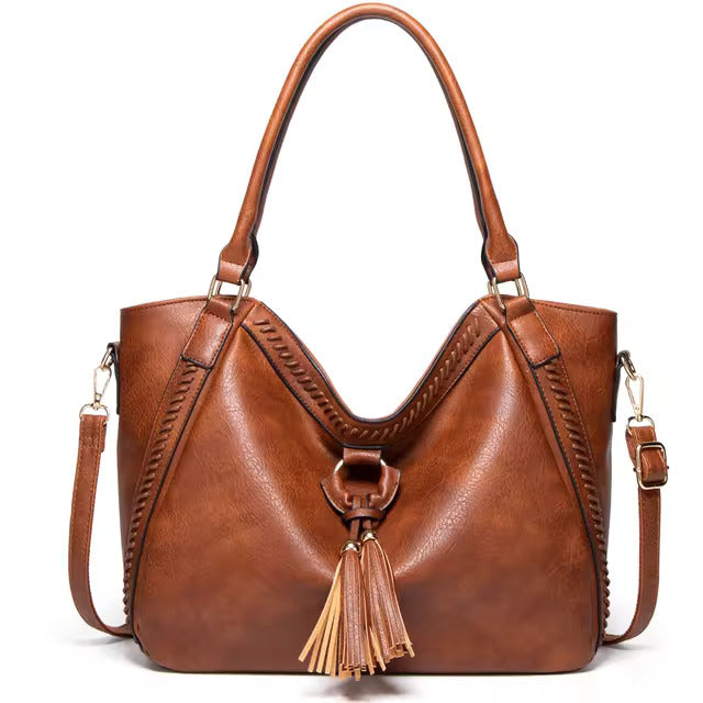 A woman carrying a soft tasselled shoulder bag while out for a walk in town.
