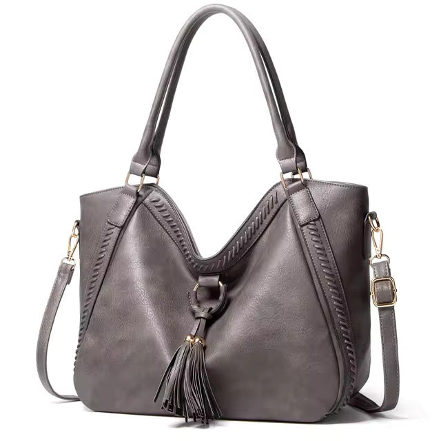 A woman carrying a soft tasselled shoulder bag while out for a walk in town.