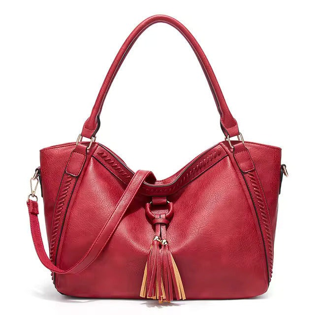 A woman carrying a soft tasselled shoulder bag while out for a walk in town.