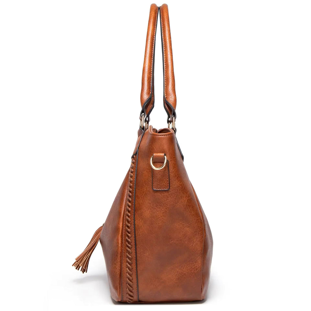 A woman carrying a soft tasselled shoulder bag while out for a walk in town.