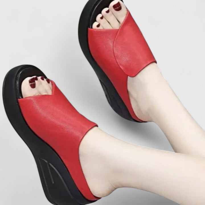 A woman stepping out in black wedge sandals paired with a summer dress.