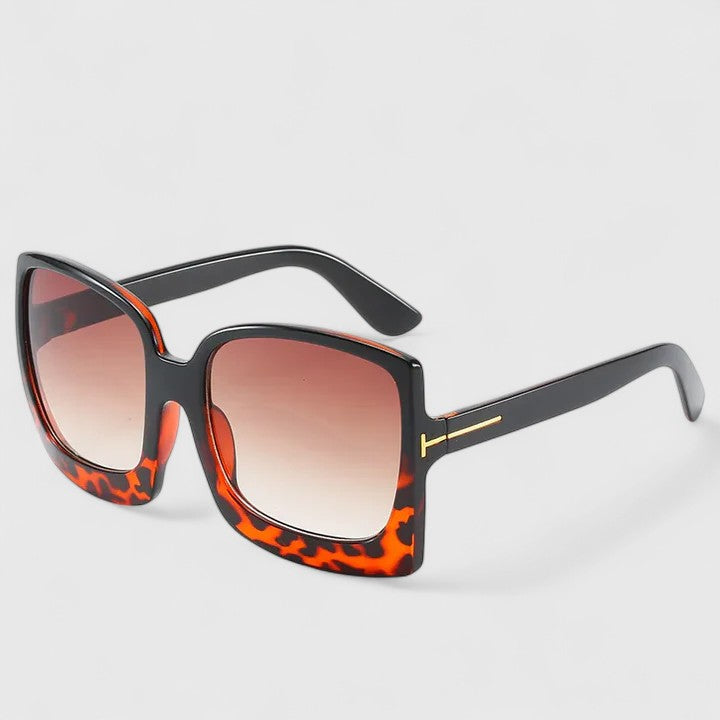 A woman on a sunny day wearing oversized gradient sunglasses, poised and glamorous.