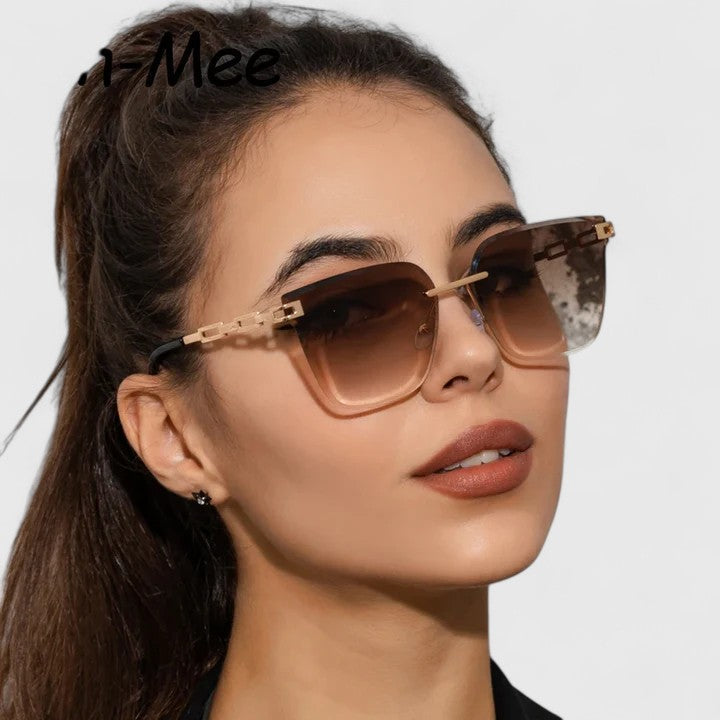 A woman wearing bold square sunglasses with brown gradient lenses and gold-tone chain-link arms.