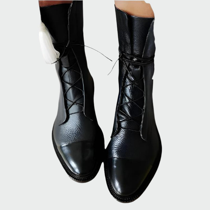 A woman in skinny jeans wearing slim black lace-up boots with a matte and glossy finish.