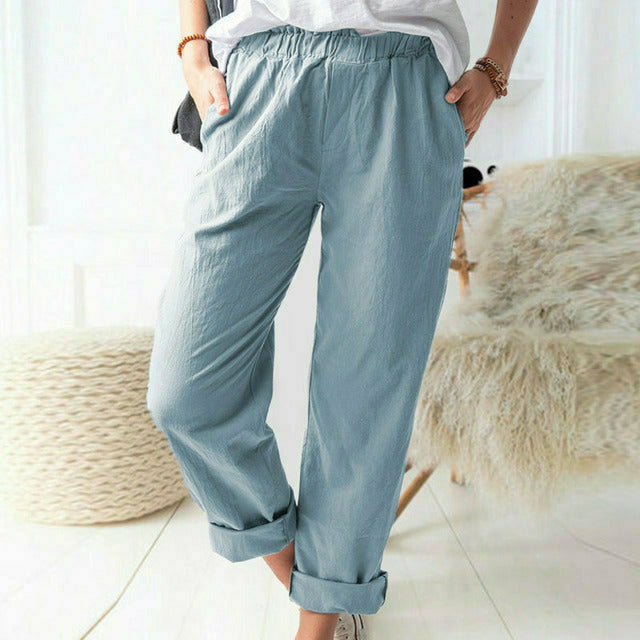A woman standing relaxed in soft straight-leg pants with a clean, elegant everyday look.