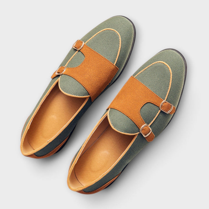 A woman wearing cream and tan round-toe slip-on loafers with twin gold buckle straps, walking with ease.
