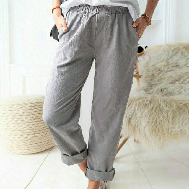 A woman standing relaxed in soft straight-leg pants with a clean, elegant everyday look.
