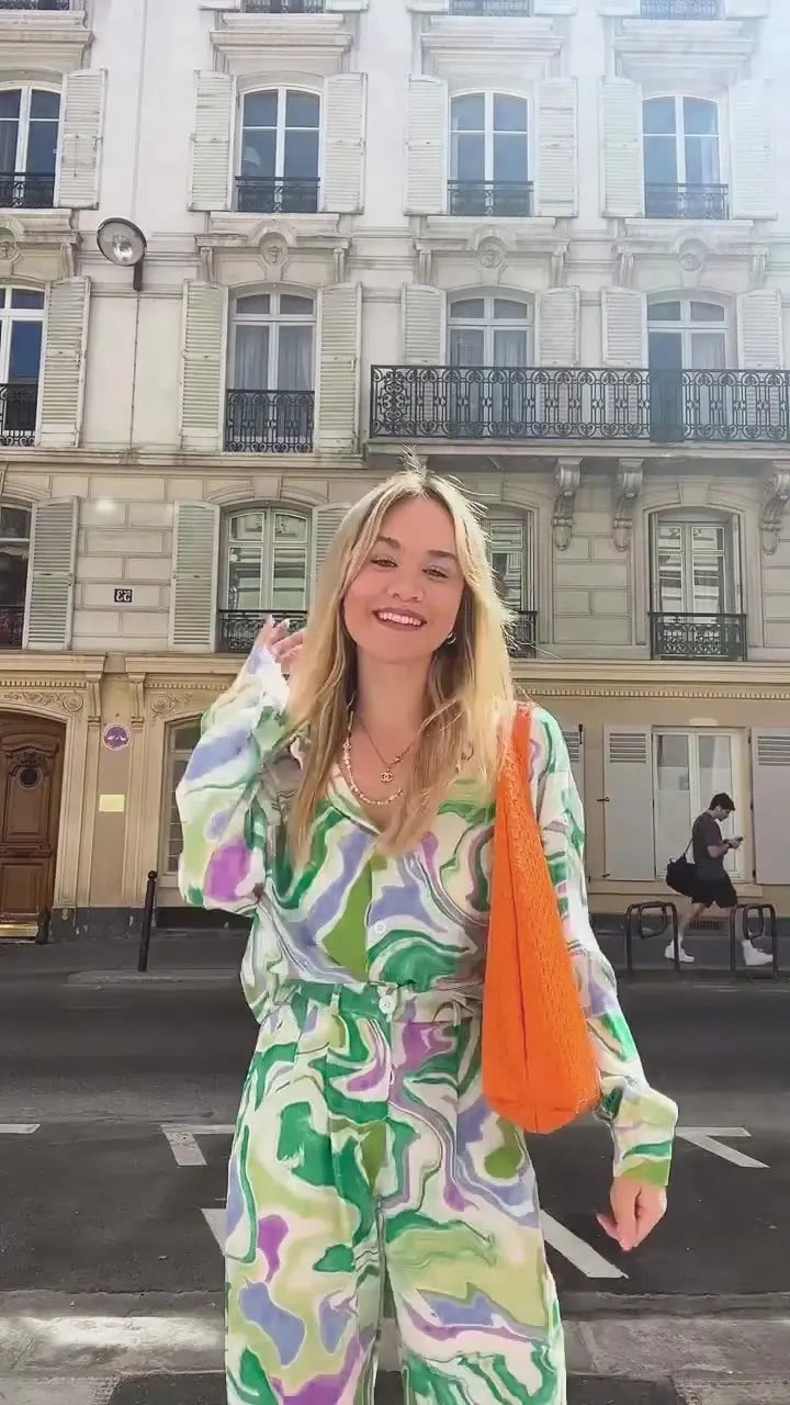 A woman wearing a bold abstract swirl-print shirt and matching wide-leg pants in the city
