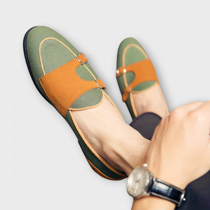 A woman wearing cream and tan round-toe slip-on loafers with twin gold buckle straps, walking with ease.