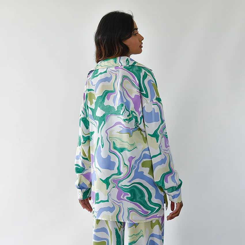 A woman wearing a bold abstract swirl-print shirt and matching wide-leg pants in the city