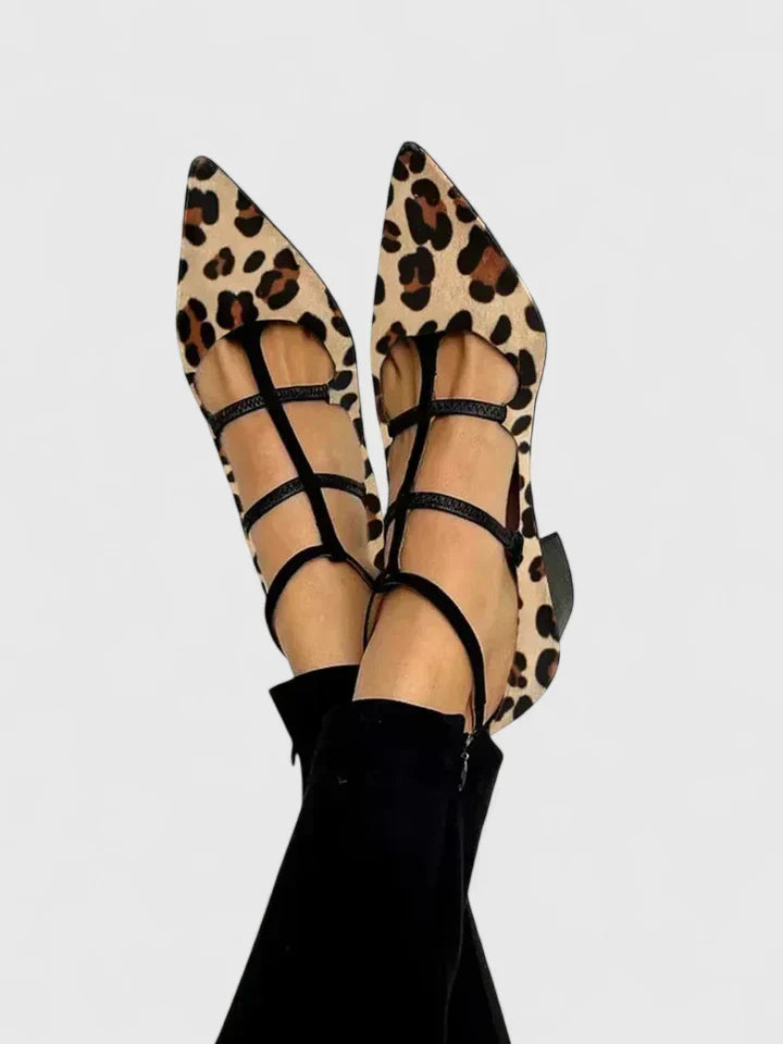 A woman walking through the city in black pointed-toe block heels with slim ankle straps, relaxed and confident.
