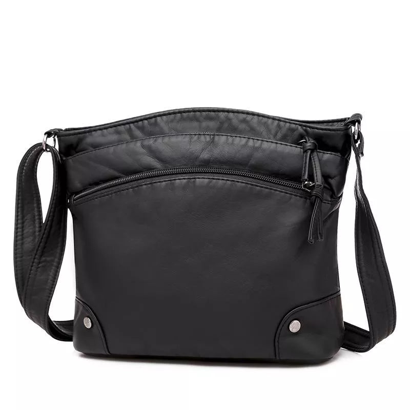 A woman wearing an elegant shoulder bag at her hip while walking through town.