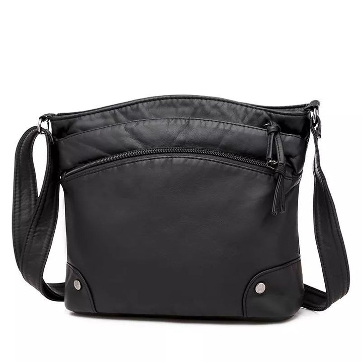 A woman wearing an elegant shoulder bag at her hip while walking through town.