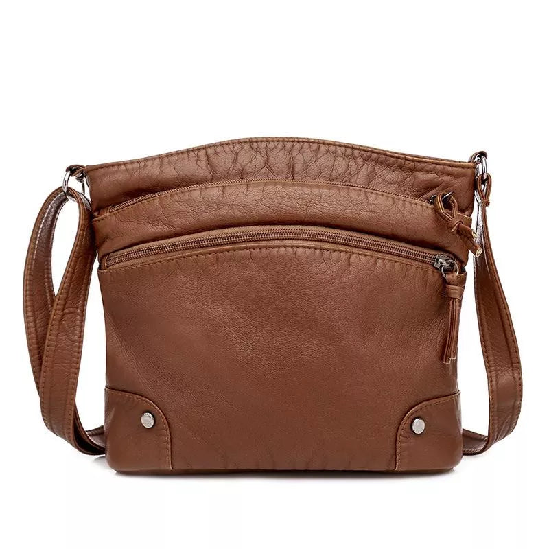 A woman wearing an elegant shoulder bag at her hip while walking through town.