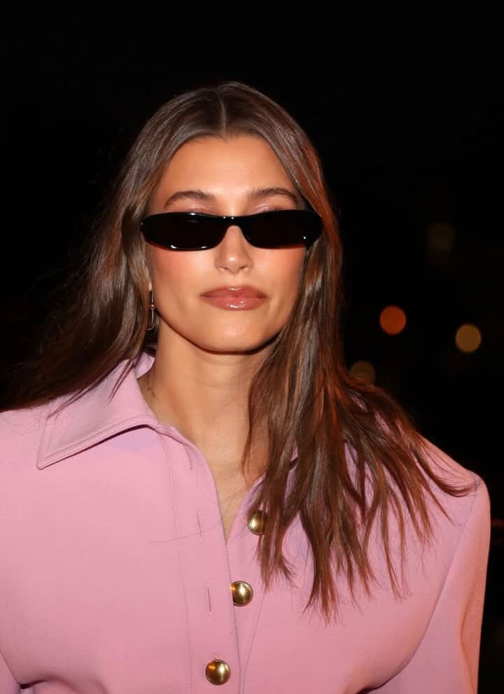 A woman wearing retro black oval cat-eye sunglasses on a sunny day.