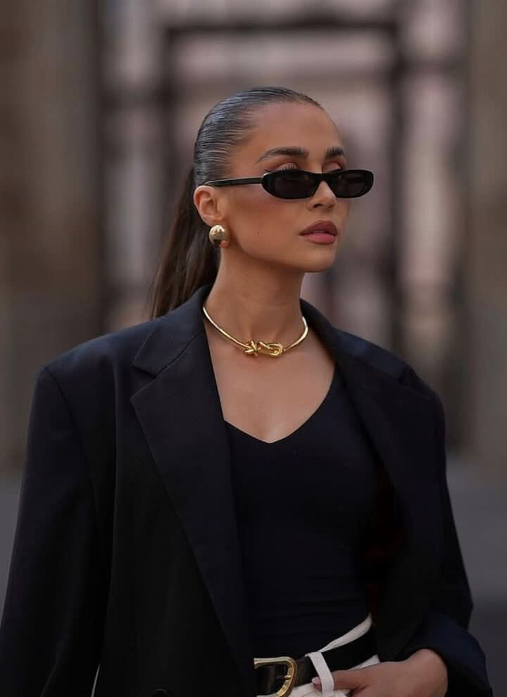 A woman wearing retro black oval cat-eye sunglasses on a sunny day.