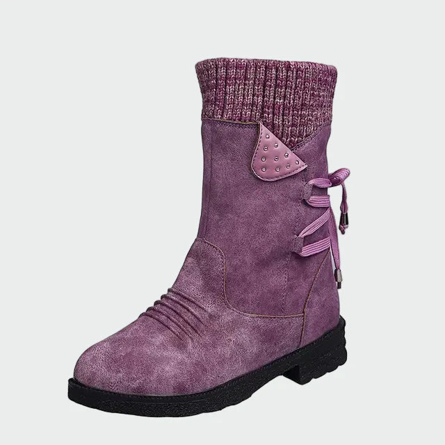 Woman wearing blue mid-calf boots with a knitted-look cuff, on a winter city street.