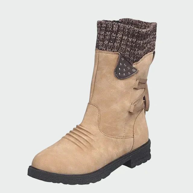 Woman wearing blue mid-calf boots with a knitted-look cuff, on a winter city street.