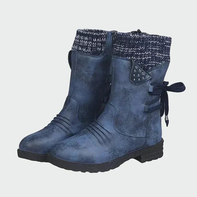 Woman wearing blue mid-calf boots with a knitted-look cuff, on a winter city street.